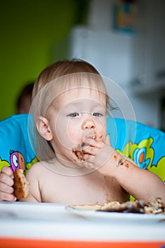 Child eats cake in the highchair
