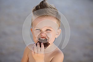 Child eats chokolate with full stength on a beach