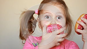 Child eats donut. Closeup baby girl eating doughnut with glase. Delicious, sweet, sweettooth