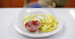 Child eats french fries with tomato sauce at table in fast food restaurant