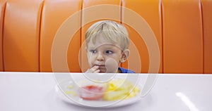 Child eats french fries with tomato sauce at table in fast food restaurant