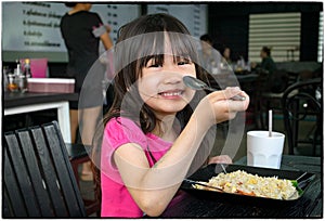 Child Eats Fried Rice with a Spoon in a Authentic Asian Restaurant.