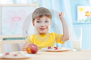 Child eats healthy food showing his strength