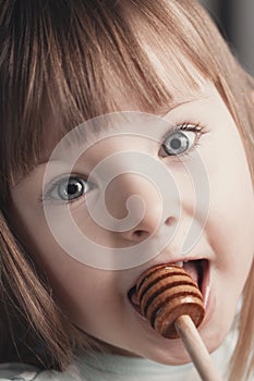 Close up portrait of funny lovely little girl eat honey
