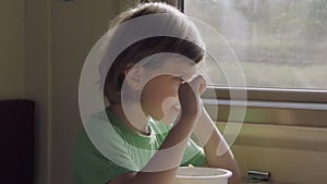 A child eats lunch sitting in a train compartment while traveling