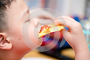 Child eats pizza with happy