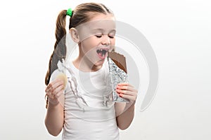 The child eats unhealthy and unhealthy food, the girl has chocolate and potato chips, portrait on a white background