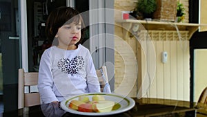 child eats a wedge-cut apple in the porch of the house. apples are a healthy food in the diet