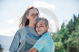 A child embraces mom in the mountain trip