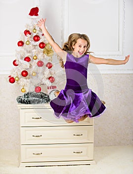 Child emotional cant stop her feelings. Girl in dress jumping. It is christmas. Day we have waited for all year finally