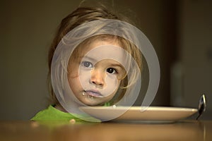 Child with empty plate, spoon after eating