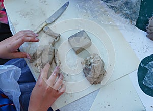 The child is engaged in modeling of plasticine sitting in the children`s table .