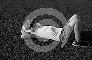 Child enjoy listens to music in headphones, laying on grass, dreaming and relaxing. Emotional funny child in t-shirt in