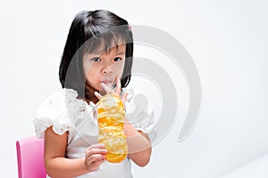 Child enjoying with bakery. Children suck her fingers stained with jam from bread. kid wearing white t-shirt aged 4 years old