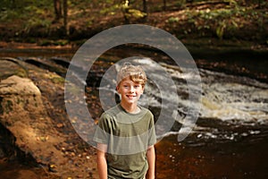 Child Enjoying a Nature Hike Along a Waterfall in the Forest in Fall