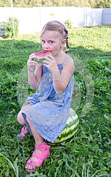 The child enjoys eating delicious, red, ripe, juicy, appetizing watermelon.