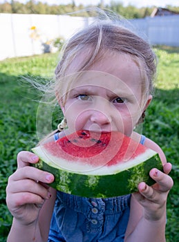 The child enjoys eating delicious, red, ripe, juicy, appetizing watermelon.