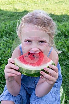 The child enjoys eating delicious, red, ripe, juicy, appetizing watermelon.