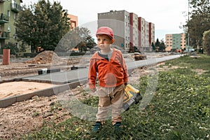 Child with excavator near construction site, dreams to be an engineer. Little builder. Education, and imagination