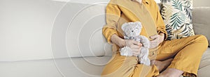 Child expecting. Family planning. Pregnancy. Pregnant woman relaxing on home sofa with teddy bear baby toy. Natural
