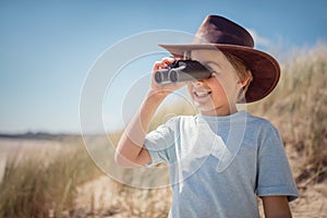 Child explorer with binoculars at the beach