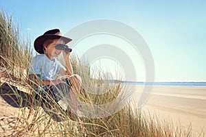 Child explorer with binoculars at the beach