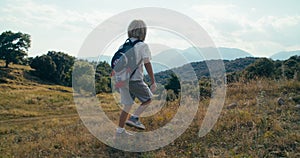 Child exploring new places on summertime hike journey with backpack