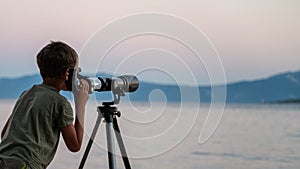 Child exploring the sky looking through a telescope