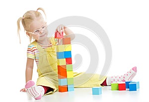 Child in eyeglases playing building blocks photo