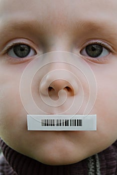 Child face with barcode sticker on mouth. Individual identifier.