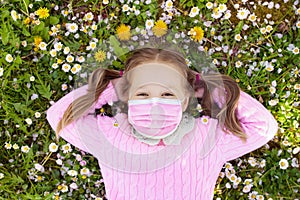 Child in face mask on lawn with flowers