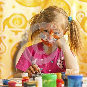 Child with a face painted with colorful paints (squares series)