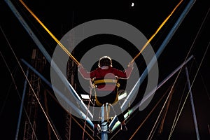 Child at a fair jumping on a Bungee Trampoline during the night