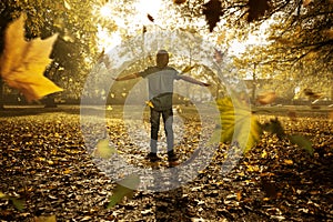 Child between falling autumn leaves