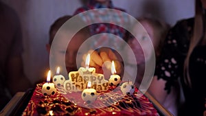 A child in a family circle puts out soccer candles on his birthday.