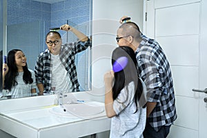 Child and father combing hair in front of the mirror