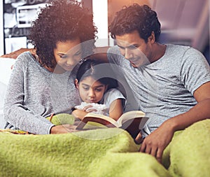 Child, father and mother reading book in a family home for story time on a lounge sofa with a smile. A woman, man and