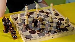 Child and father playing chess while spending time together at home. Dad and son are play board games at table.