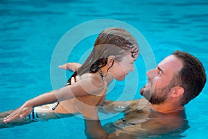 Child and father playing in swimming pool