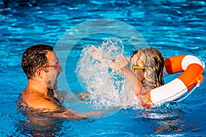 Child and father playing in swimming pool