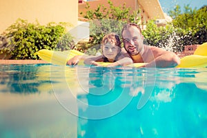 Child and father playing in swimming pool
