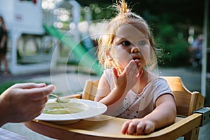 Child feading with soup at the restaurant garden