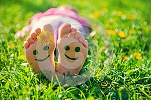 Child feet on the grass drawing a smile. Selective focus.