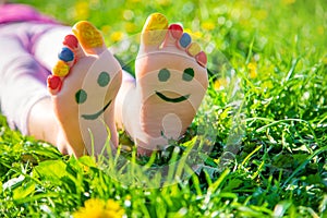 Child feet on the grass drawing a smile. Selective focus.