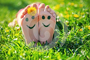 Child feet on the grass drawing a smile. Selective focus.