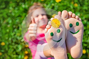 Child feet on the grass drawing a smile. Selective focus.