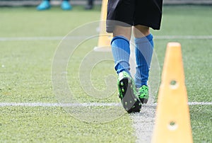 Child feet practicing running and moving on soccer field