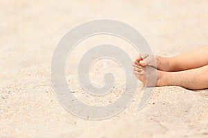 Child feet in sand at summer beach
