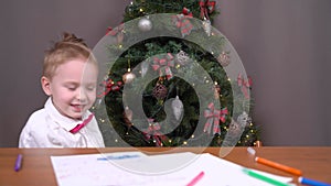 Child in festive outfit jumps out from under table showing tricks like the jack-in-the-box. Bored boy was tired of