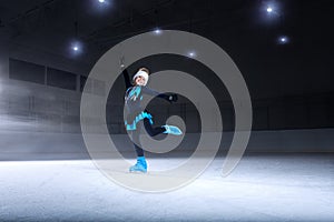 child figure skater on dark ice arena background